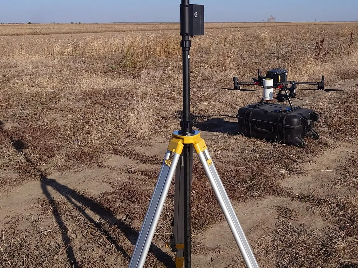 Stația de bază DJI D-RTK 2 și drona Matrice 300 RTK pregătite de zbor pe un teren agricol
